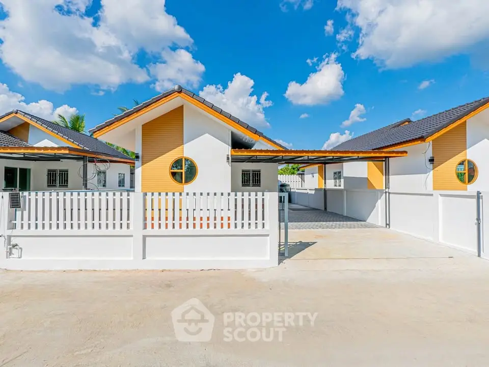 Charming modern house with vibrant facade and spacious driveway under a clear blue sky.