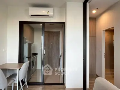 Modern apartment interior with sleek kitchen and dining area, featuring air conditioning and stylish decor.
