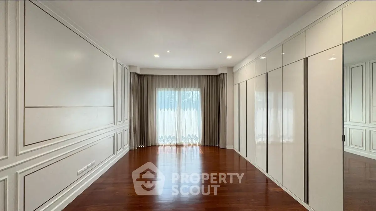Spacious empty room with elegant wood flooring and large window