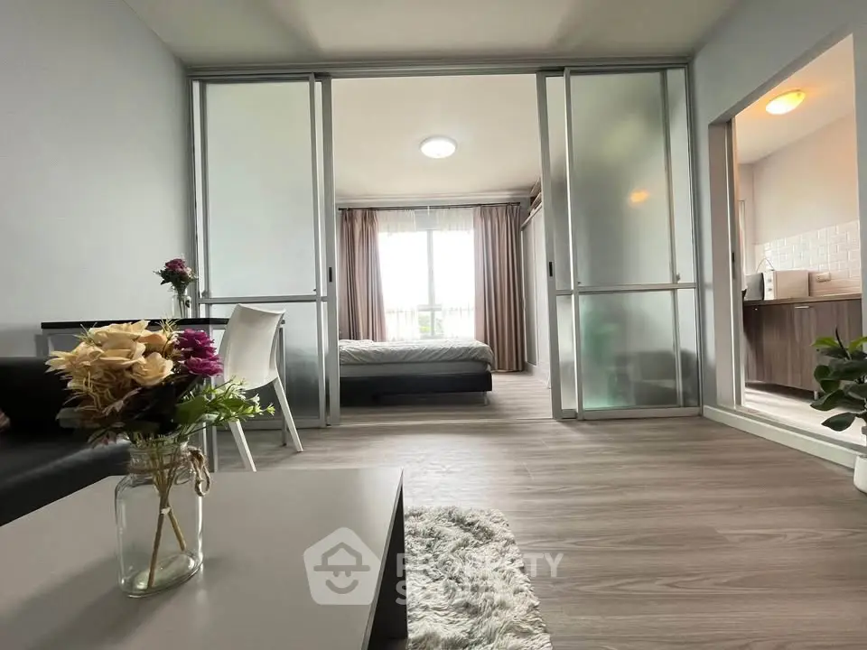 Modern open-plan living room with sliding doors leading to a cozy bedroom, featuring elegant decor and natural light.