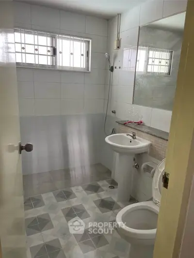 Modern bathroom with geometric tile flooring and sleek fixtures in a bright, airy space.