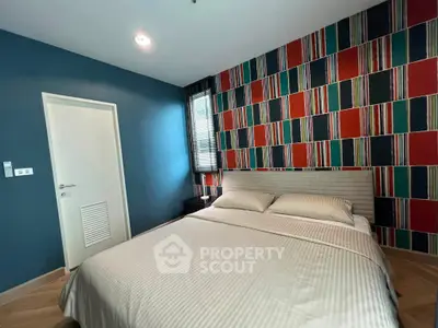 Stylish bedroom with vibrant accent wall and cozy bedding in modern apartment.