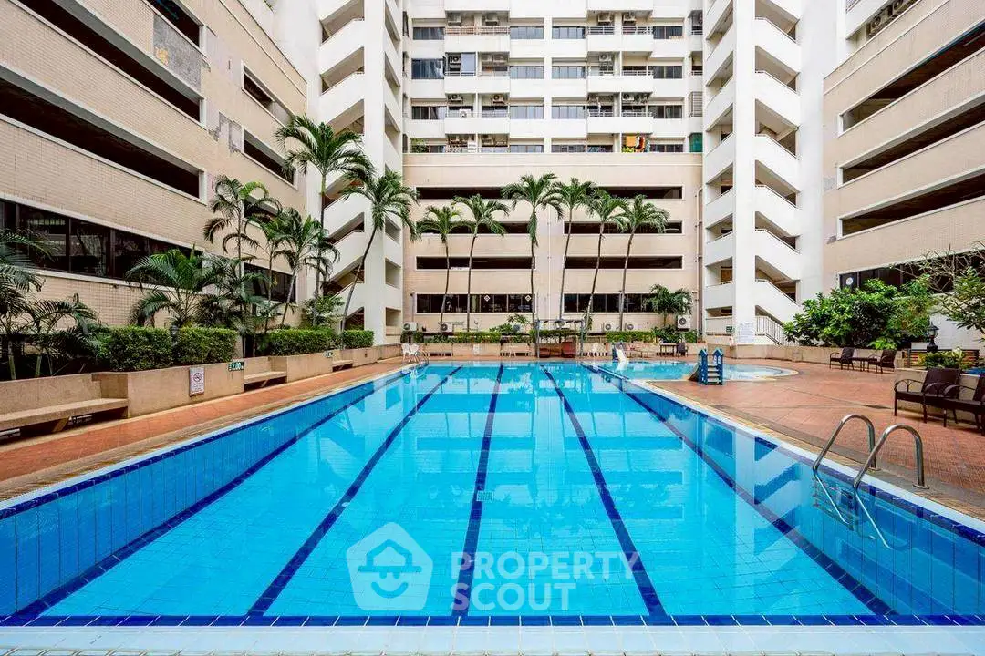 Luxurious apartment complex with a stunning outdoor pool and lush palm trees.