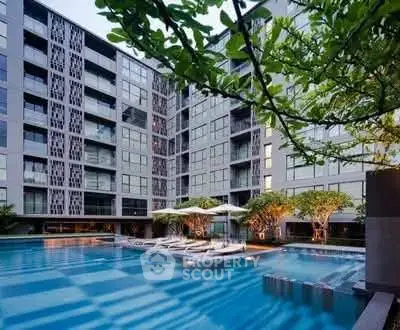 Luxurious modern apartment complex with stunning outdoor pool and lush greenery.