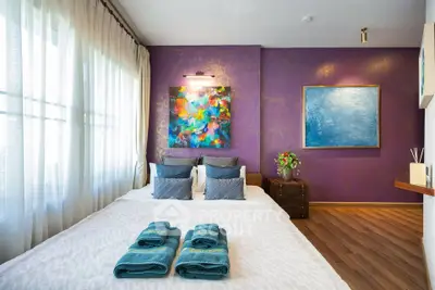 Elegant bedroom with vibrant purple accent wall and modern art decor