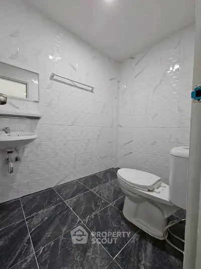 Modern bathroom with sleek white tiles and contemporary fixtures.