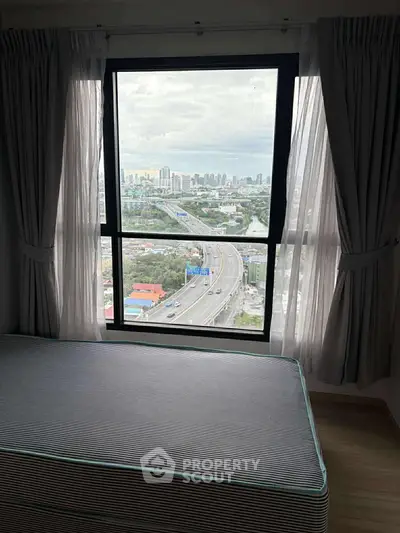 High-rise bedroom with large window offering stunning cityscape view.