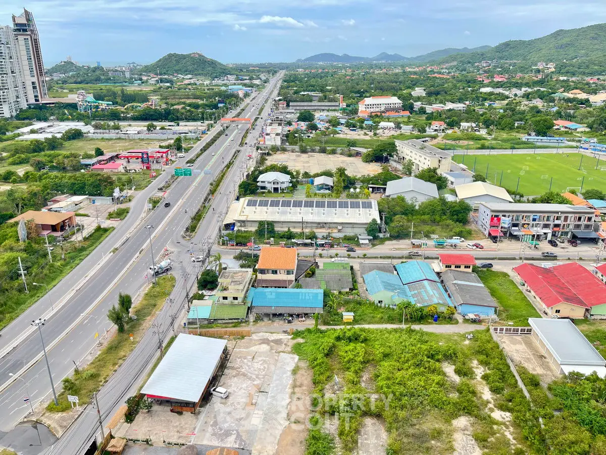 Aerial view of urban landscape with roads, buildings, and greenery, showcasing potential real estate development.