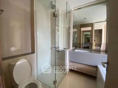Modern bathroom with glass shower and sleek vanity in contemporary home.
