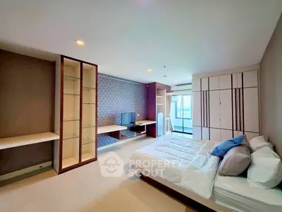 Spacious modern bedroom with built-in shelves and large windows offering natural light.