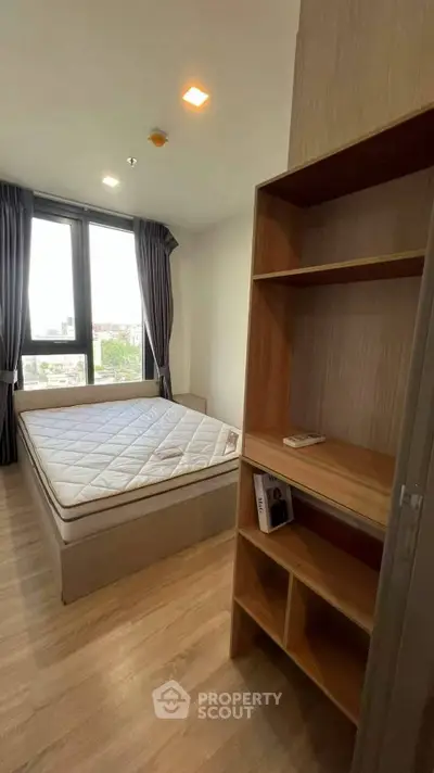 Cozy bedroom with large window and wooden shelving, perfect for natural light lovers.