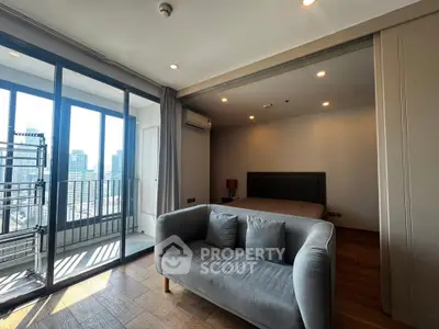 Modern studio apartment with balcony and city view, featuring cozy sofa and bed in open layout.