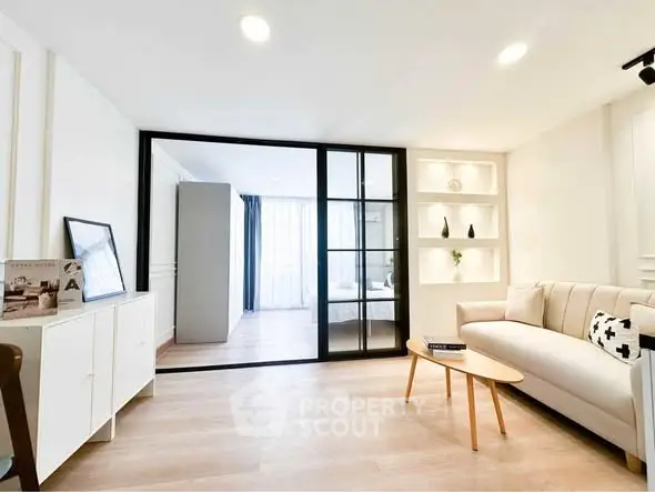 Modern living room with sleek design and glass partition leading to bedroom.