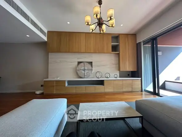 Luxurious modern living room with elegant chandelier and large sliding glass doors to balcony.