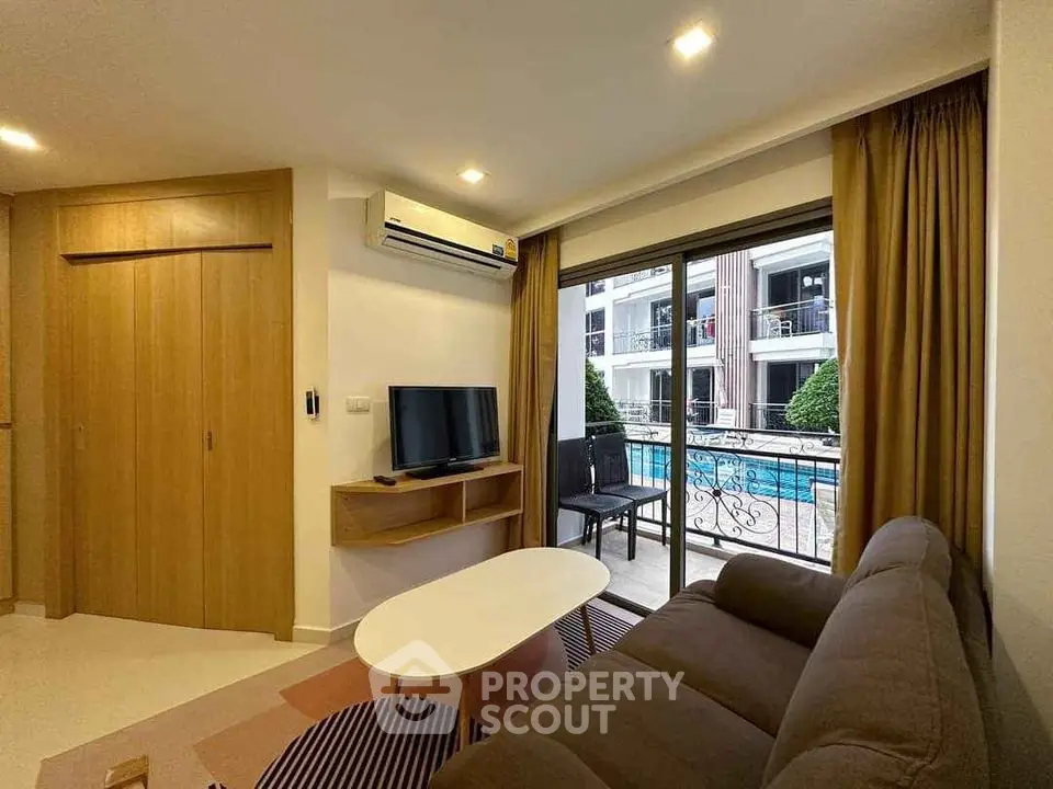 Modern living room with pool view, featuring cozy sofa and flat-screen TV, perfect for relaxation.