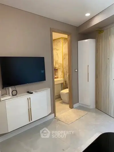 Modern apartment interior with sleek TV setup and elegant bathroom entrance.