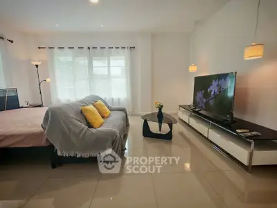Spacious living room with modern decor and large TV, perfect for relaxation.