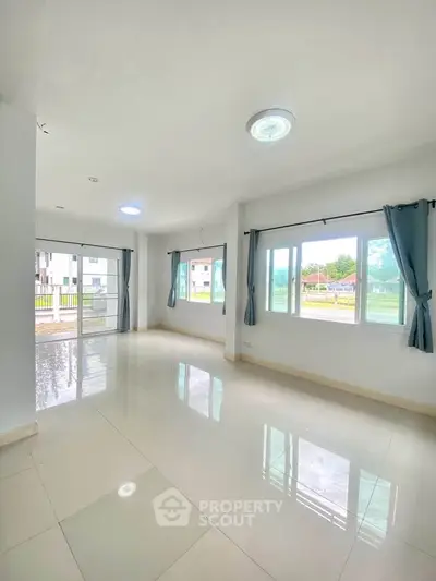 Spacious and bright living room with large windows and tiled flooring