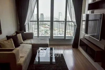 Modern living room with city view, featuring a cozy sofa and large TV, perfect for relaxation.