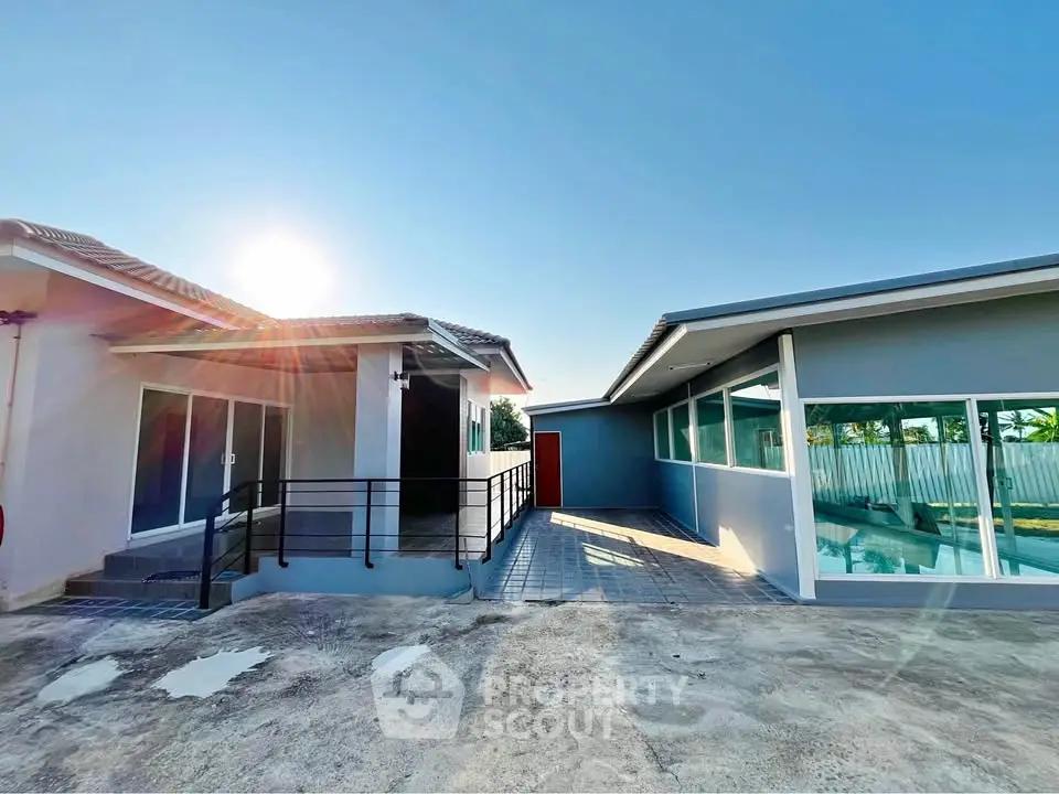 Modern single-story home with pool and spacious outdoor area under clear blue sky.