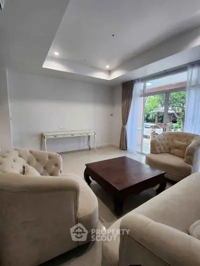 Elegant living room with plush seating and large windows offering natural light and garden view.