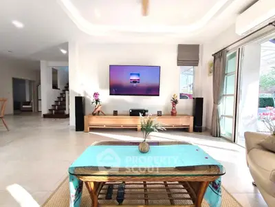 Spacious living room with modern decor and large TV, perfect for relaxation and entertainment.