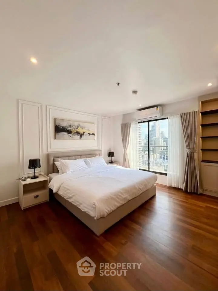 Spacious bedroom with city view and elegant decor, featuring hardwood floors and modern furnishings.