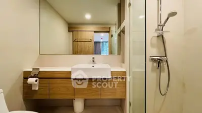 Modern bathroom with sleek wooden cabinetry and glass shower enclosure