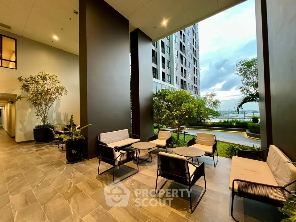 Modern apartment building entrance with stylish outdoor seating and lush greenery.