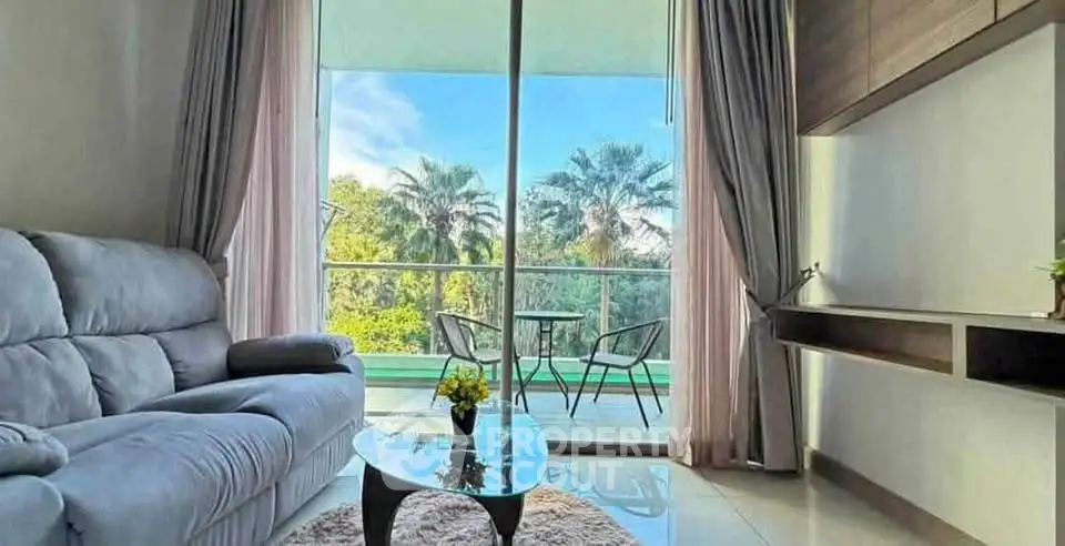 Spacious living room with balcony offering lush green views, perfect for relaxation and entertaining.