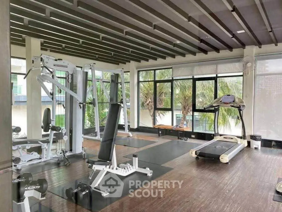 Spacious modern gym with large windows and fitness equipment in a luxury residential building.
