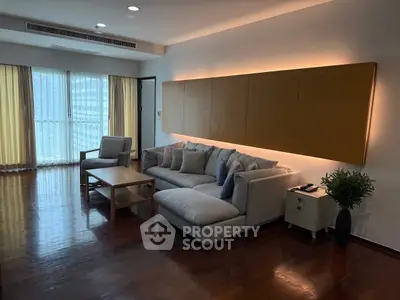 Spacious living room with modern furniture and large windows in a high-rise apartment.