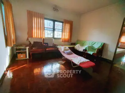 Cozy living room with natural light and wooden flooring, featuring comfortable seating and curtains.