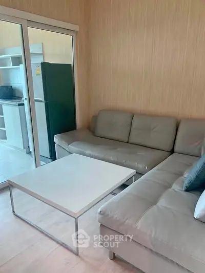 Modern living room with sleek furniture and open kitchen layout in a stylish apartment.