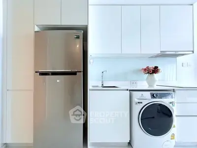 Modern kitchen with sleek appliances including fridge and washing machine, white cabinetry, and stylish decor.