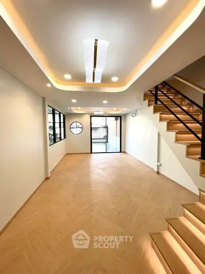 Spacious modern living room with elegant lighting and wooden staircase