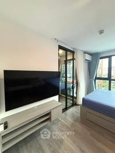 Modern bedroom with large TV and balcony view in stylish apartment.