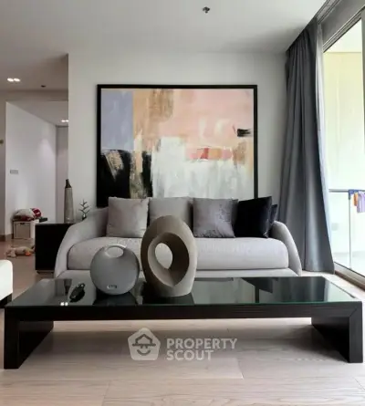 Modern living room with stylish decor and large glass doors leading to a balcony.