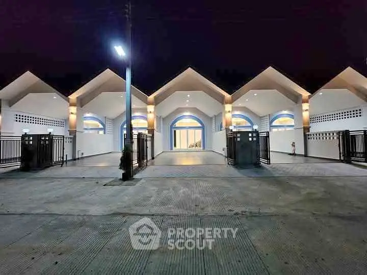 Modern architectural building with unique roof design and illuminated entrance at night.