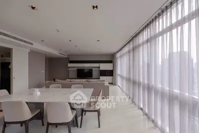 Spacious modern living room with large windows and elegant dining area