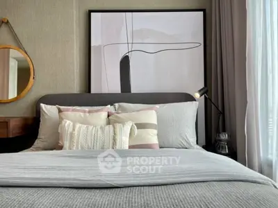 Modern bedroom with stylish decor and cozy bedding, featuring abstract art and natural light.