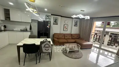 Modern open-layout living room with sleek kitchen and stylish decor, featuring a cozy sofa and dining area.