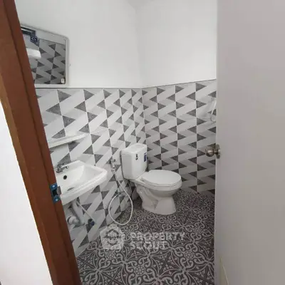 Modern bathroom with geometric tile design and compact layout.