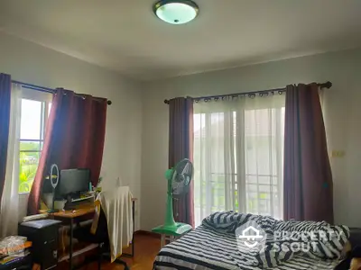 Cozy bedroom with natural light, featuring a workspace and stylish decor.