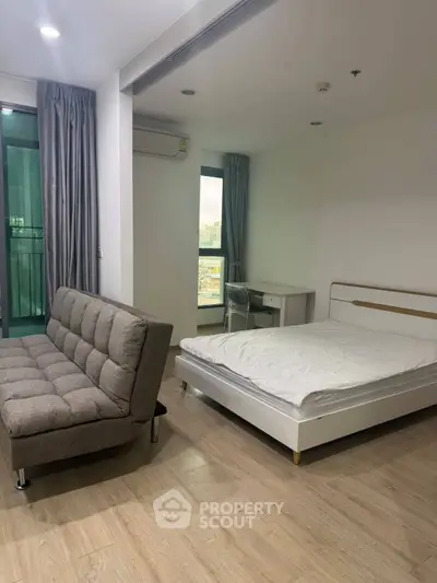 Modern studio apartment with bed, sofa, and balcony view