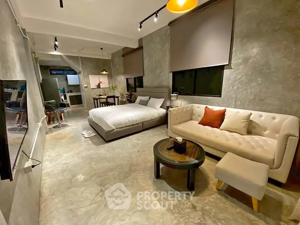 Modern studio apartment with stylish decor and open layout, featuring a cozy bed and elegant seating area.
