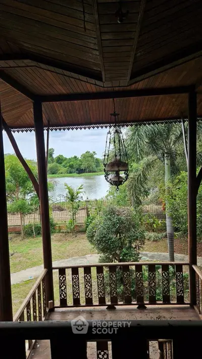 Charming wooden balcony with scenic lake view and lush greenery.