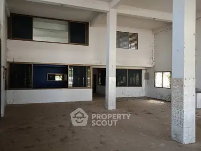 Spacious industrial warehouse interior with high ceilings and large windows for natural light.