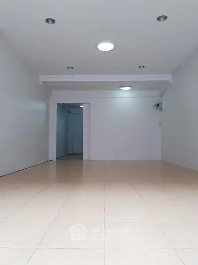 Spacious empty room with tiled flooring and recessed lighting, ideal for customization.