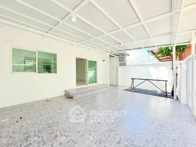 Spacious covered patio with tiled flooring and large windows, perfect for outdoor gatherings.